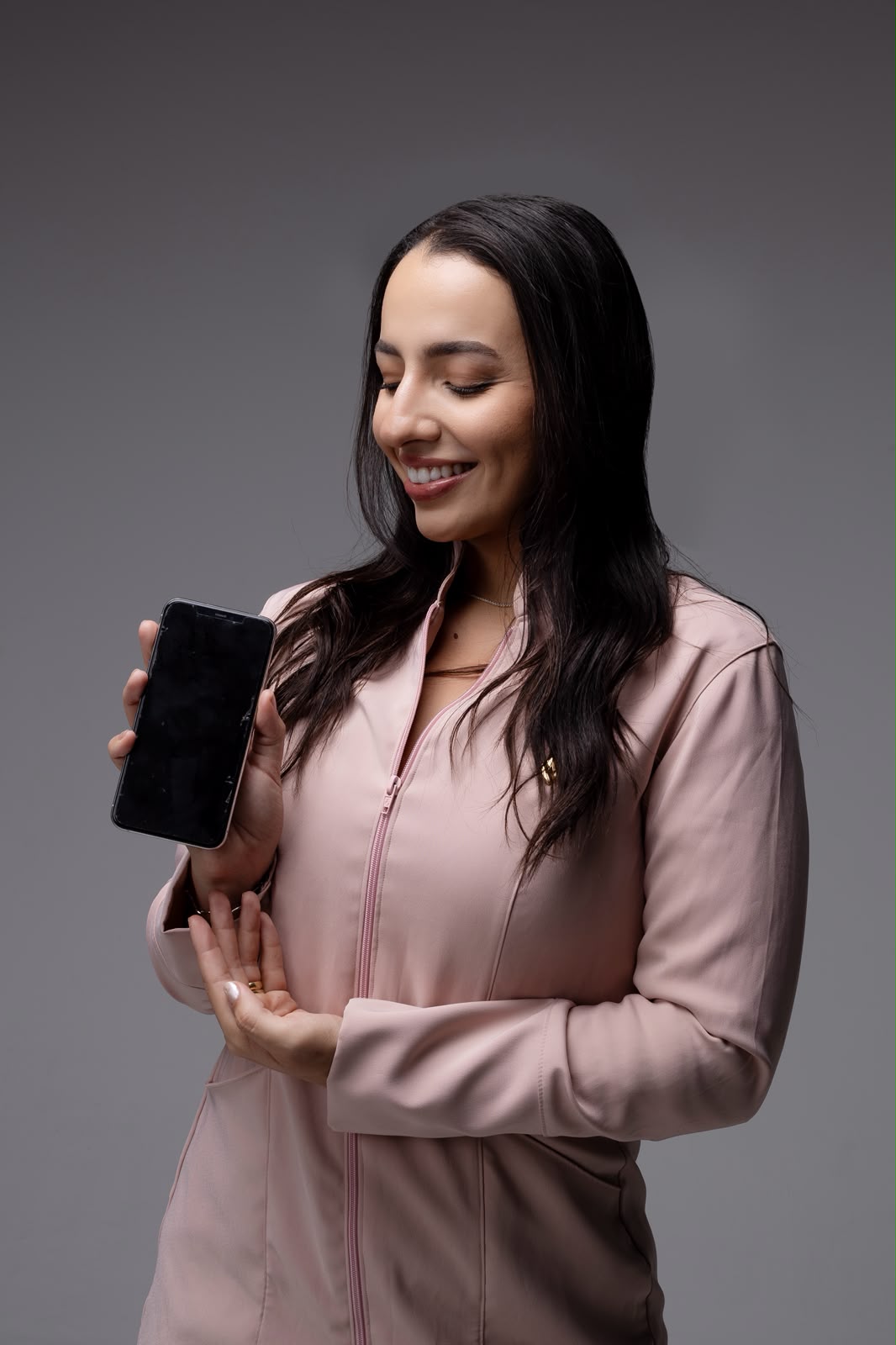 Dra. Isabela de uniforme rosa, sorrindo enquanto olha para o celular.